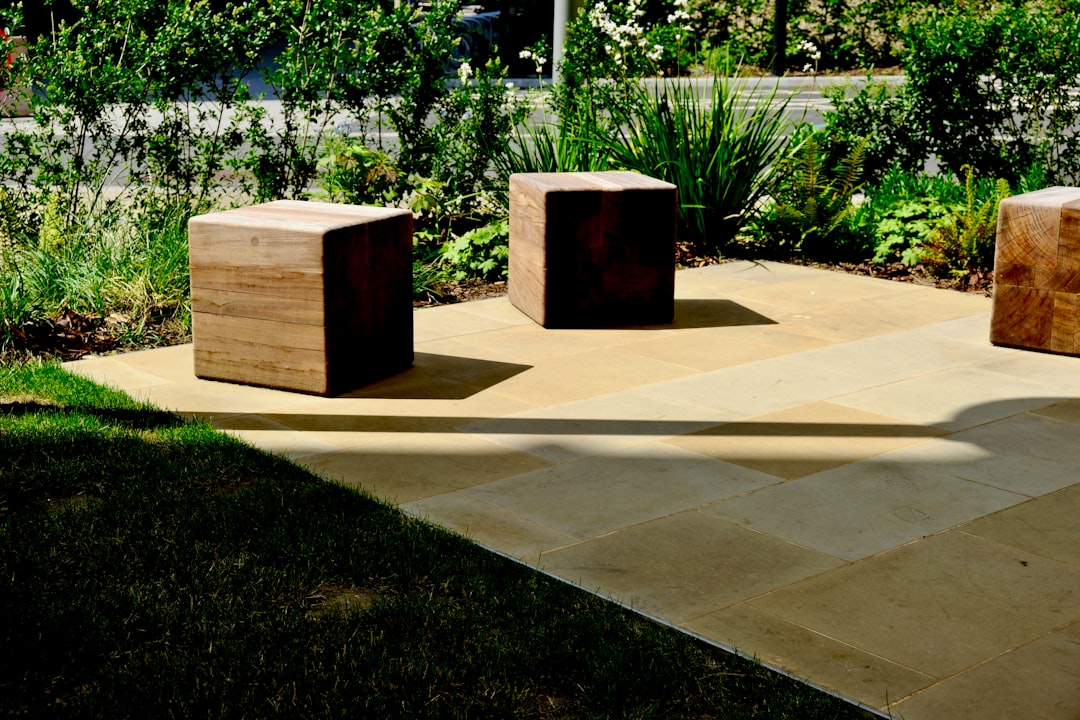 Three wooden cubes on a paved patio surrounded by greenery.